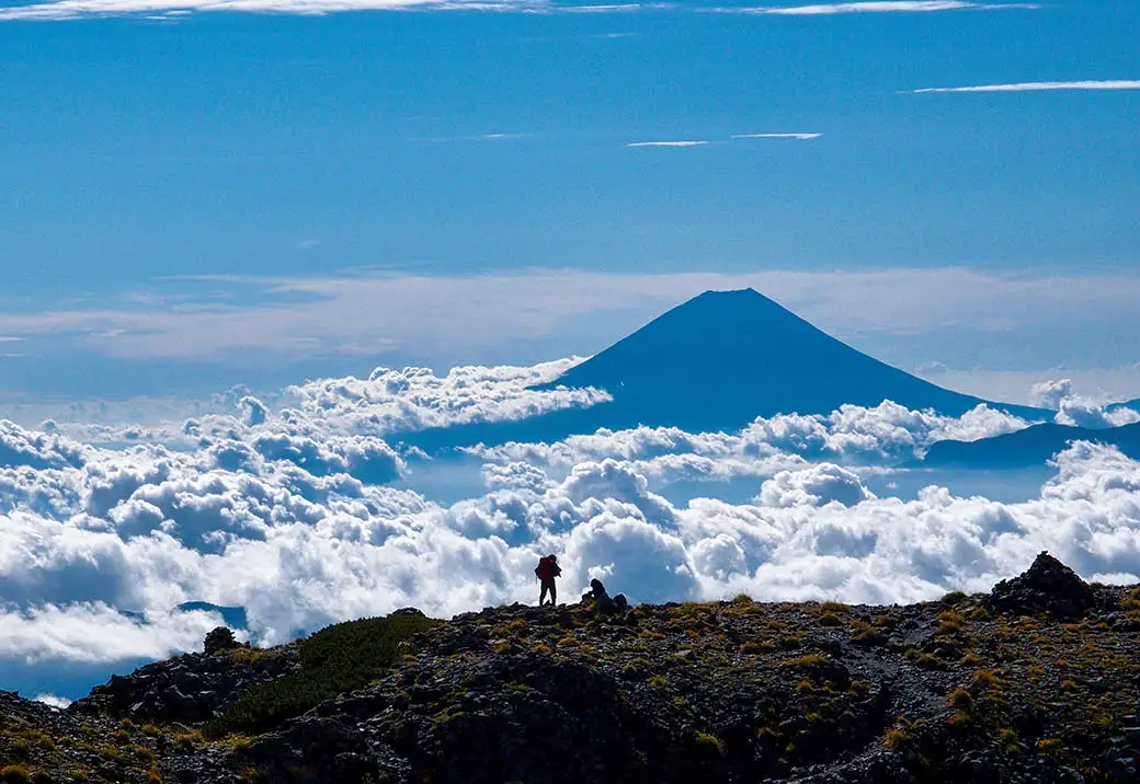 Hikers overlooking Mt Fuji above the clouds in Yamanashi Japan